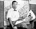 Bill Levitt poses with full-page newspaper advertisements for Levittown