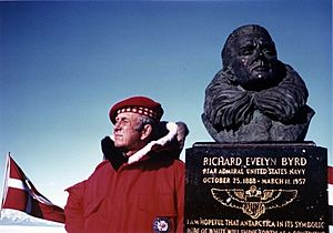 Laurence Gould posing next to a bust of American polar explorer Richard Evelyn Byrd. 1977