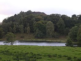 A narrow lake with a small hill directly behind it