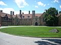 Meadow Brook Hall is made of light-colored brick with much architectural detail, in the Tudor style