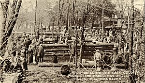 Sepia photograph of men constructing a log cabin.