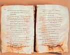 A photograph of two pages of a book written in a Greek script. The lower portions of both pages are damaged.