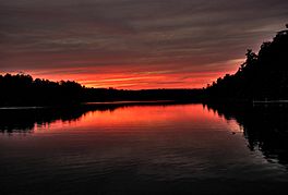 Wooded banks of the lake silhouetted against deep red sky