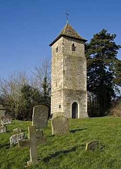 A plain tower with a pyramidal roof, a small lancet window, and a small louvred bell opening