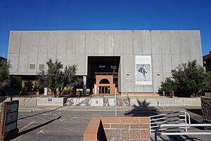 A gray, monolithic building with a few small trees in front