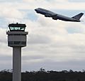 A plane taking off, with a control tower in the foreground