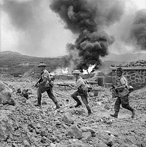 Men of 1st Battalion advance past a burning fuel store on Pantelleria.jpg