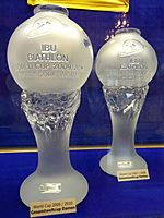 Two identical trophies, glass columns with globes on top, the left one closer to the camera, are pictured in front of a blue background.