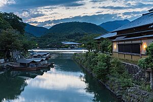 Katsura River bank with pleasure boats and illuminated building at sunset Kyoto Japan