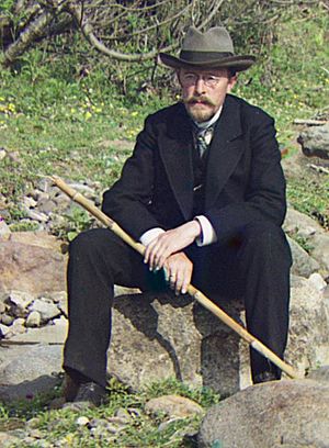 Prokudin-Gorsky seated on a rock holding a walking cane