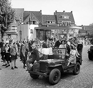 Dutch civilians ride on a jeep during the advance towards Nijmegen