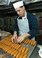 US Navy 040703-N-3986D-034 Electrician^rsquo,s Mate Fireman Noel Martinez of Patterson, N.J., places corn dogs on a tray to be baked in the galley aboard USS George Washington CVN 73