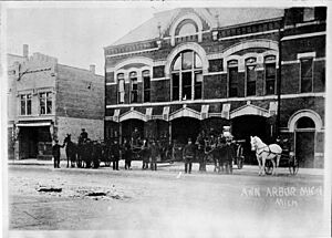 The men, horses, and equipment of the Ann Arbor Fire Department standing in front of the station, Huron Street