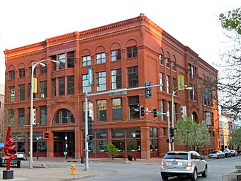 alt=A large four-story red brick building with many windows. The building is on a street corner with the front and one of the sides visible.
