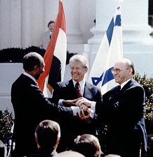 Anwar Sadat, Jimmy Carter, and Menachem Begin shaking hands on the White House grounds