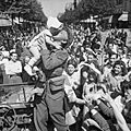 An AFPU photographer kisses a small child before cheering crowds in Paris, 26 August 1944. BU18
