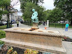 A large, rectangular, pink granite base with a smaller, aged bronze state of a boy and turtle sitting in the center of the base.