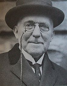 Smiling old man with round glasses wearing a hat