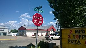 Bilingual French/English stop sign and street signs at 50th Street and 50th Avenue
