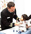 US Navy 031027-N-0000W-001 Family Nurse Practitioner Lt. Cmdr. Michael Service cares for a young girl at the U.S. Naval Hospital (USNH) Yokosuka