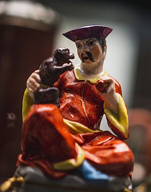 Porcelain; man seated on plinth, holding monkey and ball. Meissen factory. British Museum 1948,1203.64 (detail)