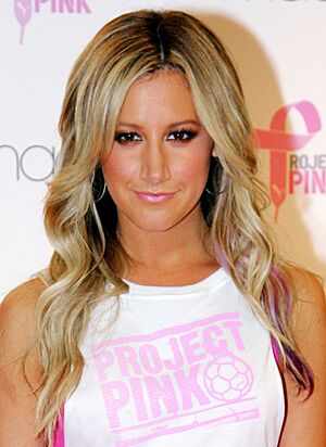 A woman with long blonde hair wearing a white t-shirt.