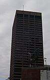 Ground-level view of a rectangular skyscraper with a dark brown facade and prominent black windows