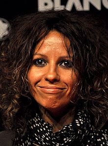 Woman with dark hair and dark eyes looking at the camera and smiling