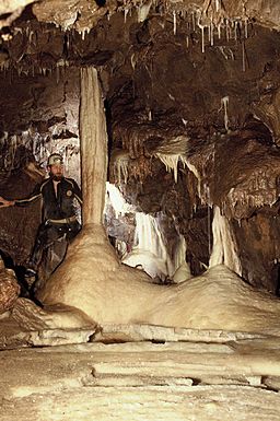Potholler standing by pillar in limestone cave