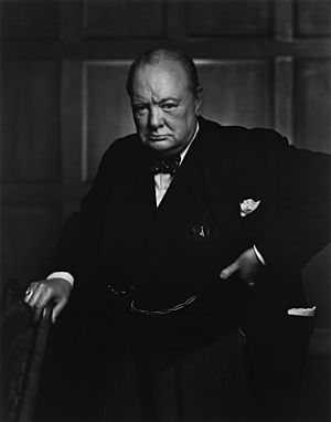 Churchill wearing a suit, standing and holding a chair