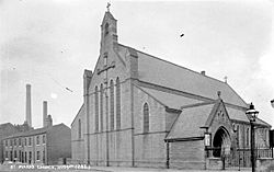 19th century stone church with side aisles and bell gable, pictured in 1910