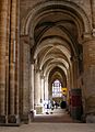 A side aisle with masonry of massive proportions is ribbed with arches of a bold profile.