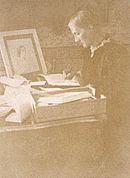 Julia writing letters at her desk in the drawing room of Talland House in 1892. On the desk is a drawing of her mother by Watts