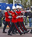 Four soldiers marching in red-and-blue dress uniforms
