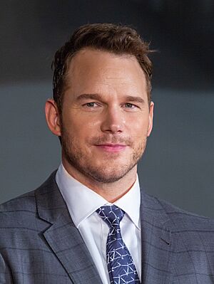 Head shot of Pratt smiling at the camera while wearing a suit and tie