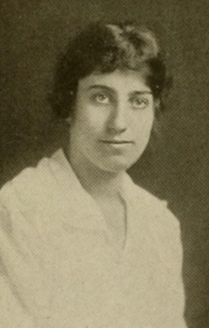 A young white woman with dark hair, wearing a white blouse or dress