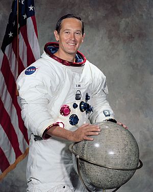 Duke posing in spacesuit with a Moon globe