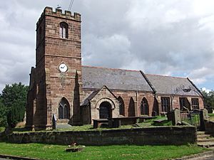 A red sandstone church seen from the south with a battlemented tower on the left