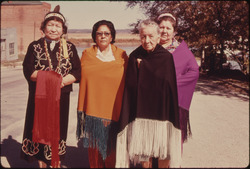 FOUR WOMEN OF THE IOWA INDIAN TRIBE ARE SHOWN WEARING A MODERN VERSION OF THEIR COSTUMES ON THE MAIN STREET OF WHITE... - NARA - 557158.tif