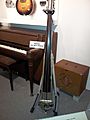A museum exhibit of vintage musical instruments shows a 1930s amplifier and speaker cabinet and an upright bass with a pickup.