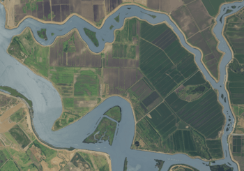 An aerial photograph of an island covered in farmland and surrounded by rivers. The island looks like a triceratops, facing left, being punched in the solar plexus from below.