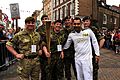 An Olympic torchbearer, right foreground, holds the torch amid members of the Guard of Honour May 24, 2012, in Gloucester, England 120524-O-ZZ999-003