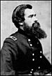 Profile of a white man with a long beard and thick hair wearing a double-breasted military jacket with a rectangular patch on the shoulder.