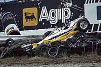 A badly damaged yellow-and-white racing car after impact into a tyre wall