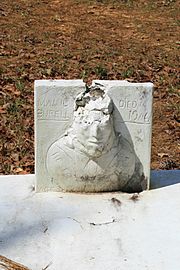 Broken single concrete gravestone with male face