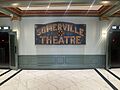Old sign in lobby of Somerville Theatre with theater entrances to the side