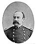 Head and shoulders of a balding white man with a drooping handlebar mustache and pince-nez glasses. He is wearing a double-breasted military jacket with shoulderboards.