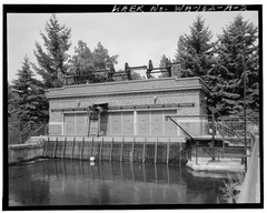 CLOSEUP OF SOUTH FACADE OF UPPER FALLS GATE HOUSE, SHOWING TRASH RACKS, REMOVABLE STEEL DOORS, TRASH RAKE STRUCTURE, AND DERRICK, WINCH AND CABLE GATE LIFTING DEVICE, LOOKING HAER WASH,32-SPOK,5A-2