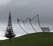 Metal sculpture that produces an optical illusion of the shape of a sheet of paper on the landscape by Neil Dawson