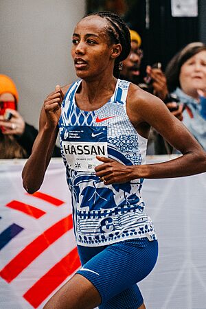 Hassan running at the 2023 Chicago Marathon. She is a black woman with dreadlocks, wearing a running outfit with her name on the front.